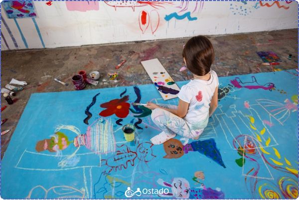 A photo of a girl in a painting room with colours every where